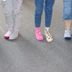 Powiększ zdjęcie Na zdjęciu stopy stojących dzieci w kolorowych skarpetkach