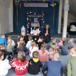 Powiększ zdjęcie Dzieci siedzą na podłodze i słuchają pani