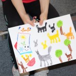 Powiększ zdjęcie Na zdjęciu praca plastyczna przedstawiająca skarpetkę koty i drzewa narysowane kredkami