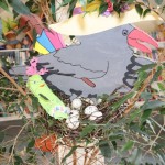 Powiększ zdjęcie Na zdjęciu kwiatek z gniazdem w nim papierowa wrona jajka i skarpetka