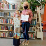 Powiększ zdjęcie W Bibliotece Rozalka z mamą laureatki konkursu trzymające dyplomy obok stoją torby z nagrodami 