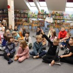 Powiększ zdjęcie Dzieci siedzą na podłodze w bibliotece