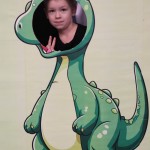 Powiększ zdjęcie Dziewczynka w fotobudce zielonego dinozaura