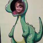 Powiększ zdjęcie Dziewczynka w fotobudce zielonego dinozaura