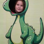 Powiększ zdjęcie Dziewczynka w fotobudce zielonego dinozaura