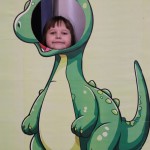 Powiększ zdjęcie Dziewczynka w fotobudce zielonego dinozaura