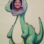 Powiększ zdjęcie Dziewczynka w fotobudce zielonego dinozaura