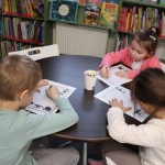 Powiększ zdjęcie Dzieci siedzą przy stolikach i rozwiązują labirynt