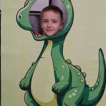 Powiększ zdjęcie Chłopiec w fotobudce zielonego dinozaura