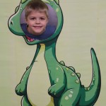Powiększ zdjęcie Chłopiec w fotobudce zielonego dinozaura