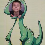 Powiększ zdjęcie Chłopiec w fotobudce zielonego dinozaura