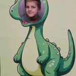 Powiększ zdjęcie Chłopiec w fotobudce zielonego dinozaura