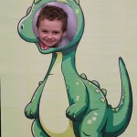 Powiększ zdjęcie Chłopiec w fotobudce zielonego dinozaura