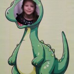 Powiększ zdjęcie Dziewczynka w fotobudce zielonego dinozaura