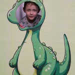 Powiększ zdjęcie Chłopiec w fotobudce zielonego dinozaura