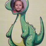 Powiększ zdjęcie Dziewczynka w fotobudce zielonego dinozaura