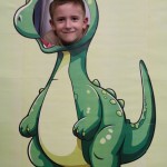 Powiększ zdjęcie Chłopiec w fotobudce zielonego dinozaura