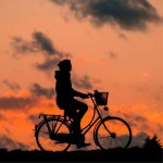 Powiększ zdjęcie Czarny cień rowerzysty w pomarańczowym zachodzie słońca
